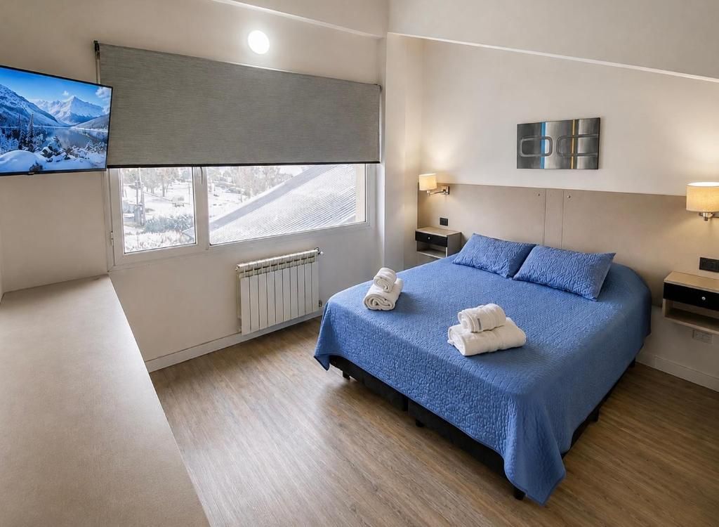 Een hotelkamer met een bed, een televisie, een raam met uitzicht en een radiator.