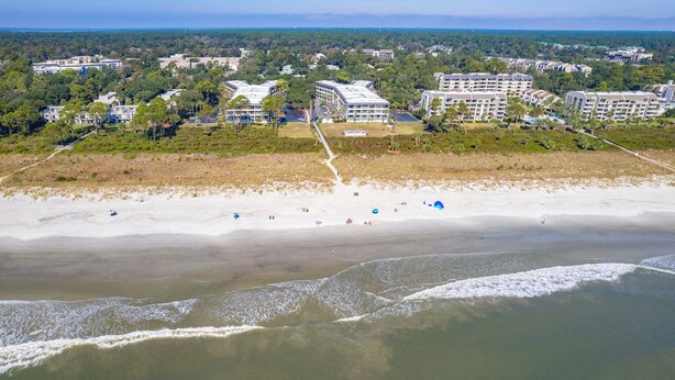 An aerial view of a coastal area with a beach, buildings, and greenery. - Ocean View, Top Floor Condo in Hilton Head (Hilton Head Island)