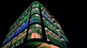 Un immeuble à plusieurs étages doté d’une architecture moderne, caractérisé par une façade incurvée et des fenêtres illuminées.