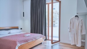 A bedroom with a wooden bed, a large window, and a sliding door leading to a balcony.