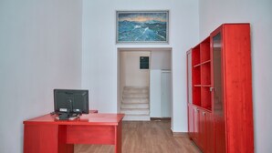 A room with a red desk, a television, a staircase, and a red cabinet.