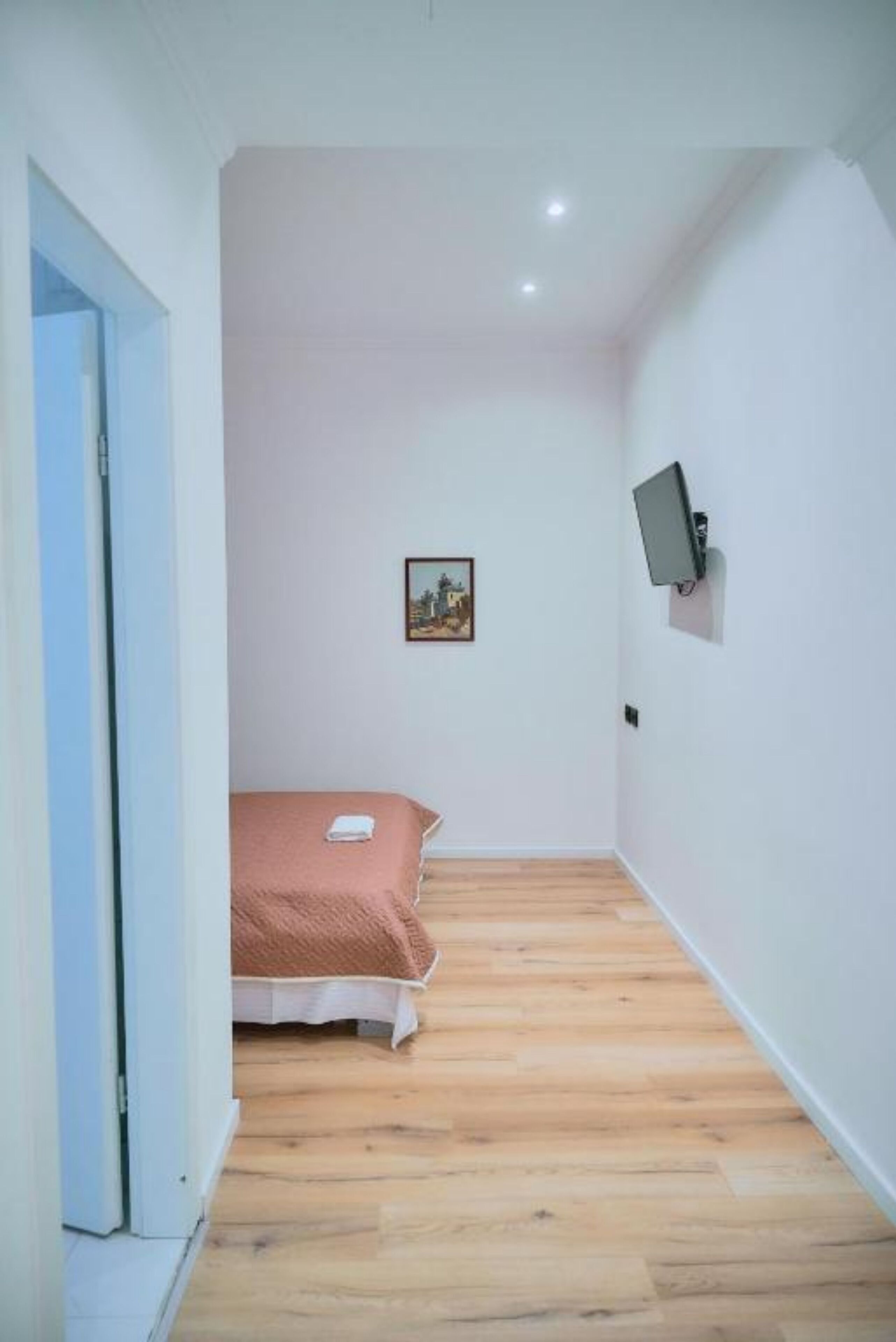 A bedroom with a bed, a television mounted on the wall, and a door leading to another room.