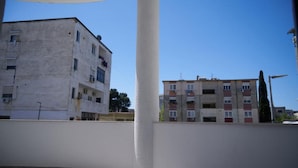 A building with multiple floors and balconies, a clear sky, and a white column in the foreground.