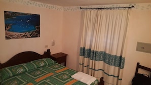 A bedroom with a bed, a nightstand, a wall-mounted picture, and a curtain. - THREE-ROOM APARTMENT RESIDENCE WITH SWIMMING POOL IN EXCLUSIVE AREA AND NEAR THE SEA (Porto Cervo)