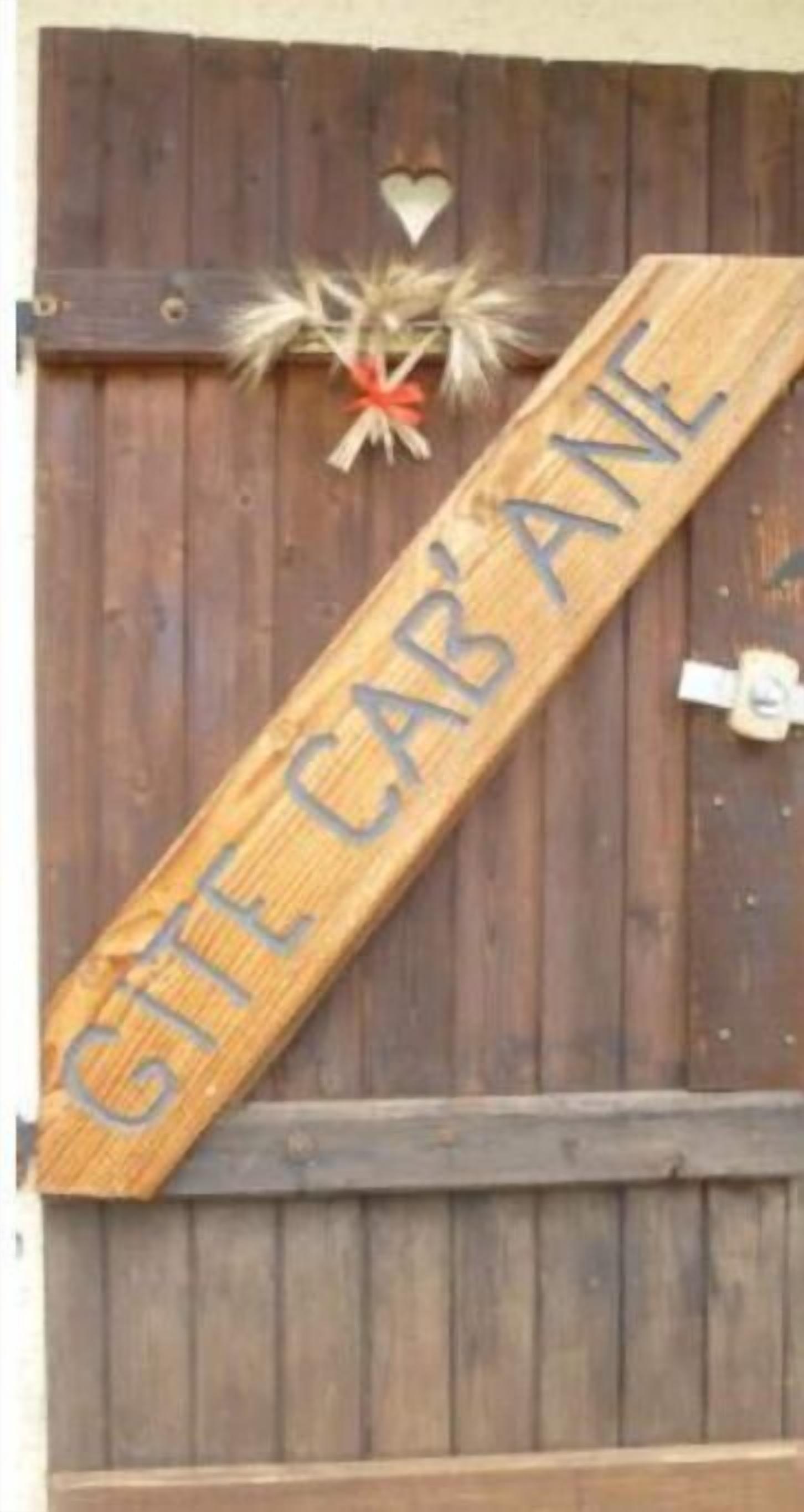 Een houten bord met de tekst 'GTE CAB' ANE' bevestigd aan een houten muur.