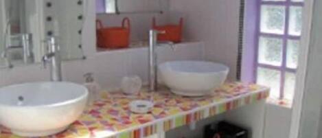 A bathroom with two sinks, a mirror, and a window.