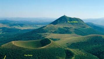 Luchtbeeld van de Puy de Dôme en Puy Pariou, met de nadruk op het bergachtig terrein en het omliggende landschap.