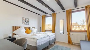 Een moderne slaapkamer met een bed, een bureau en uitzicht op gebouwen.