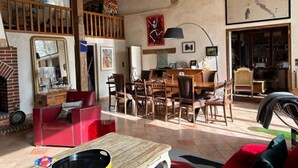 Amplia sala de estar con comedor, una escalera y una cocina visible a través de una puerta abierta.