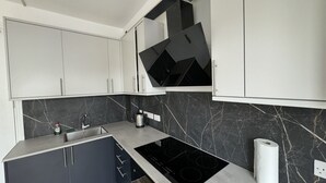 Eine moderne Küche mit weißen Schränken, einer schwarzen Arbeitsplatte und einer schwarzen Spritzschutzwand.