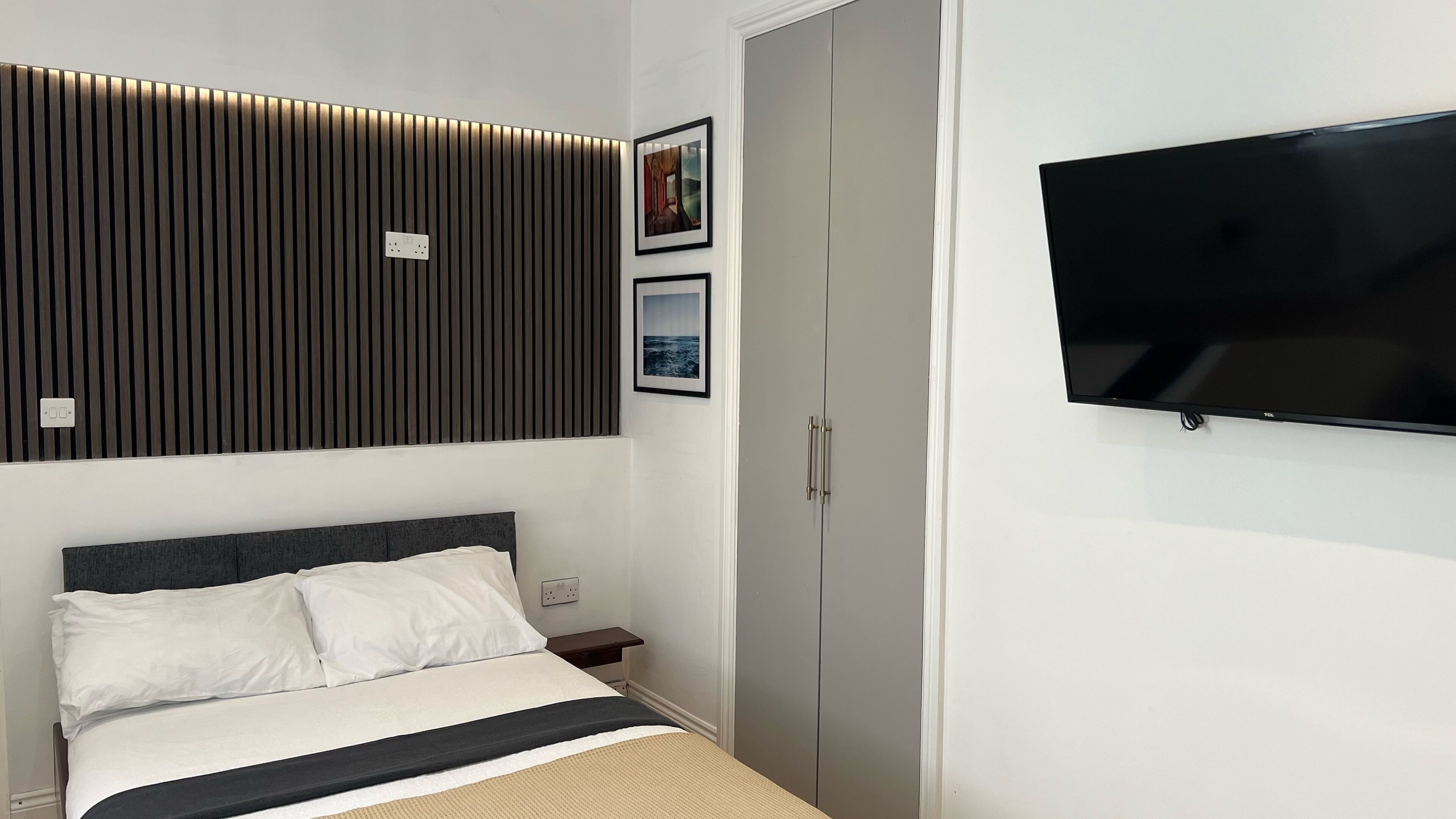 A modern bedroom with a bed, a TV, and a wardrobe.