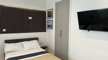 A modern bedroom with a bed, a TV, and a wardrobe.