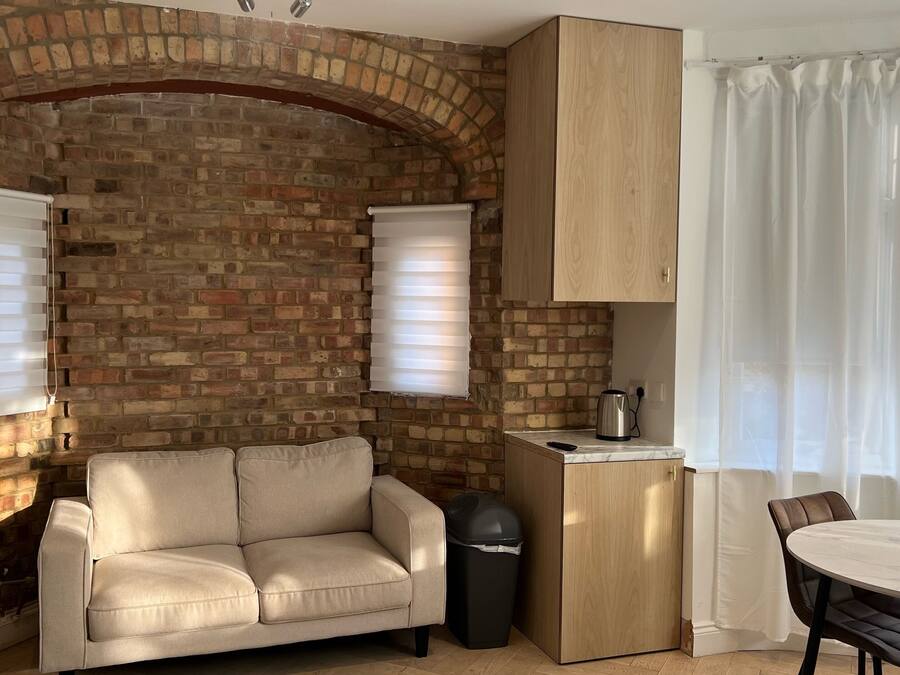 A compact living space with a brick wall, a sofa, a small table, and a cabinet.