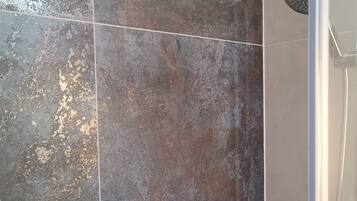 A shower area with a glass door and a showerhead.