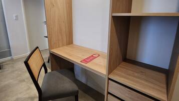 Quarto moderno com escrivaninha embutida, uma cadeira e estante.
