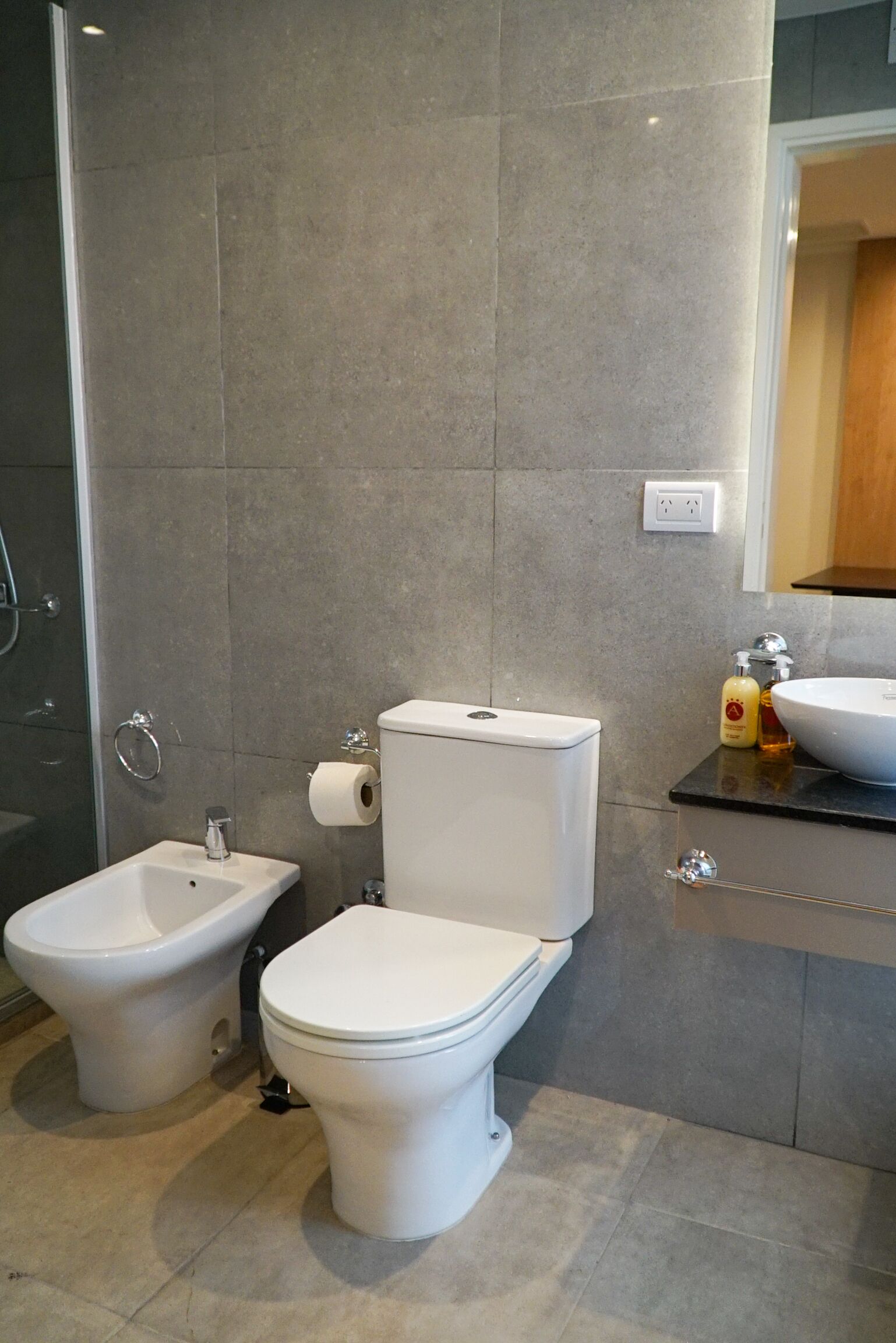A modern bathroom with a bidet, toilet, and sink.