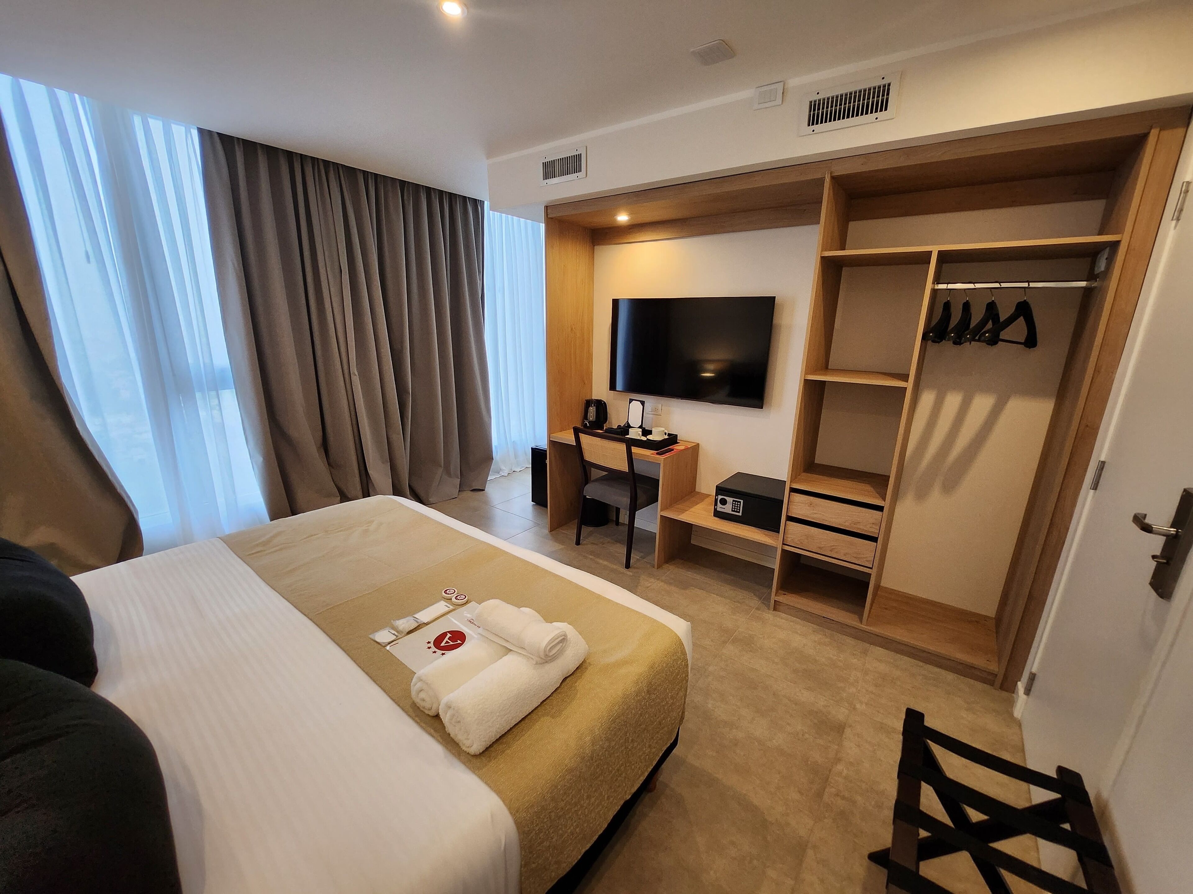 A hotel room with a bed, a desk, a TV, and a walk-in closet.
