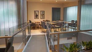 A modern hotel lobby with a glass staircase, seating area, and potted plants. - Amerian Rio Cuarto (Rio Cuarto)