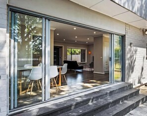 Un intérieur moderne comprenant un coin repas, un canapé noir et une porte vitrée donnant sur un patio.