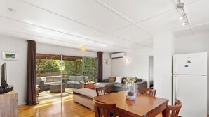 A spacious living area with a wooden dining table, a sofa, and a large window.