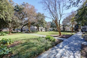 A park with a paved walkway, trees, and a grassy area. - The Gaelic Guesthouse @ Washington Square | 1890s (Savannah)