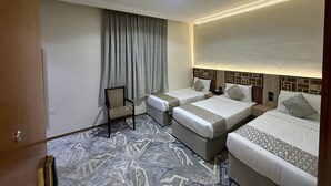 A hotel room with three beds, a chair, and a patterned carpet. - Askant Golden Hotel (Makkah)