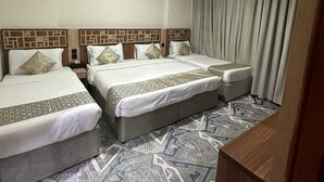 A hotel room with two beds, a patterned carpet, and a curtain on the window. - Askant Golden Hotel (Makkah)
