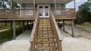 Une maison à deux étages avec un escalier en bois menant à un porche abrité.