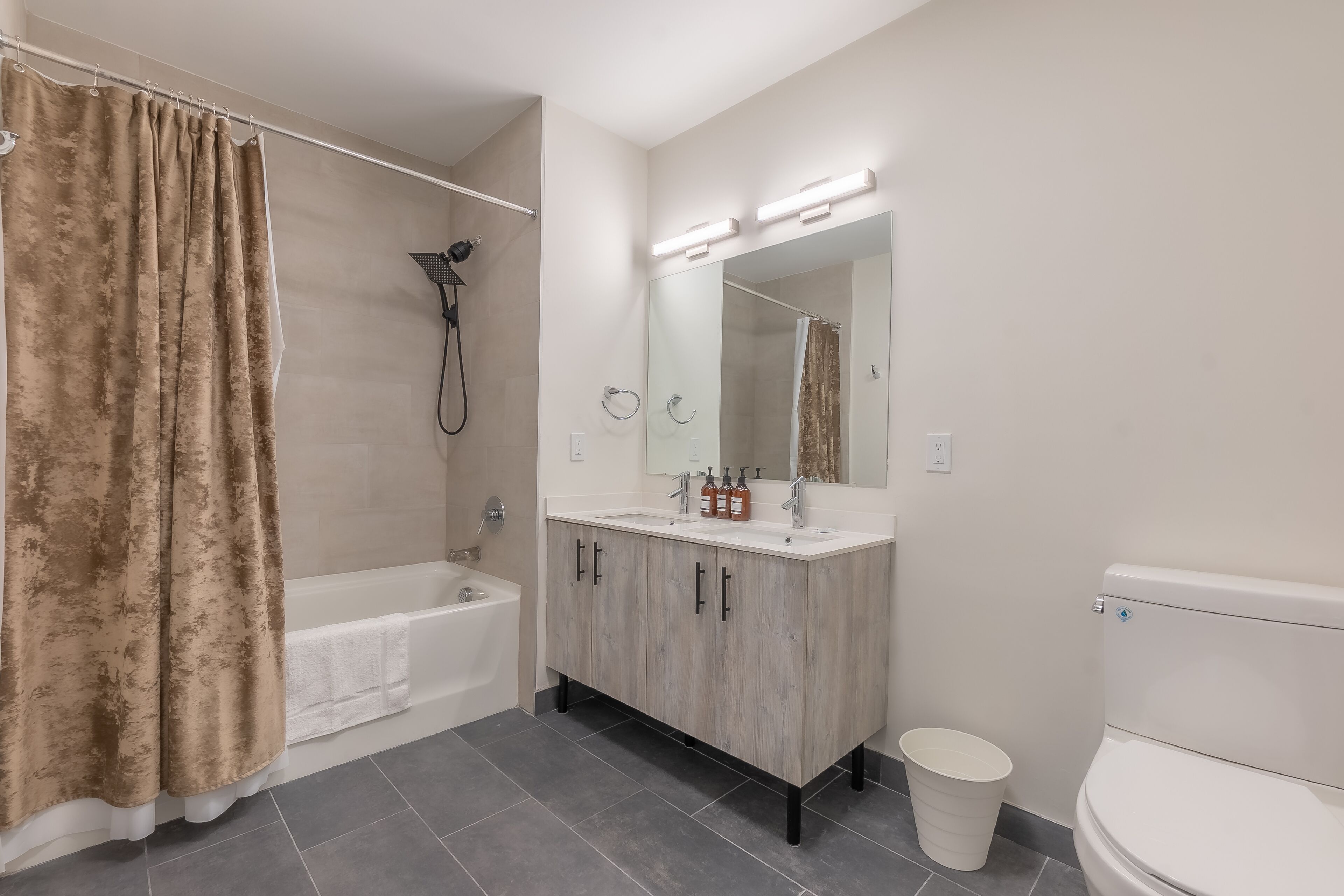 A bathroom with a bathtub, a shower, a toilet, and a vanity with a mirror.