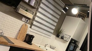 Une cuisine moderne avec des meubles blancs, un plan de travail en bois, une machine à café et un lave-vaisselle encastré.