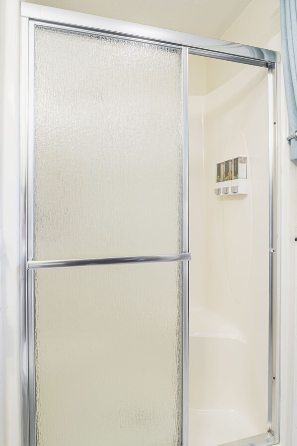 Cabina de ducha con puerta de vidrio satinado y zona interior blanca.