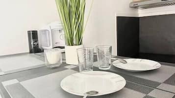 A dining table with a placemat, a candle, two glasses, and a spoon.