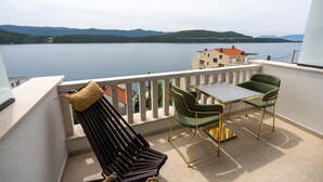 Un balcon avec une table et deux chaises, donnant sur un lac avec des montagnes en arrière-plan.