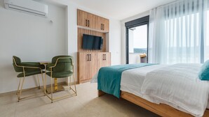 Une chambre d’hôtel moderne équipée d’un lit, d’un bureau avec deux chaises, d’une télévision et d’une armoire.