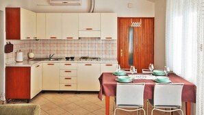 A compact kitchen with white cabinets, a tiled backsplash, and a dining area with a table set for four. - 2 bedrooms apartment Anita with BBQ (Pula)
