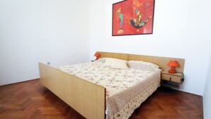 A bedroom with a wooden bed, a nightstand, a red lamp, and a painting on the wall. - 2 bedrooms apartment Anita with BBQ (Pula)