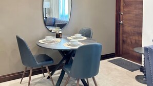 Een eetruimte met een ronde tafel, vier stoelen, een grote spiegel en een hanglamp.