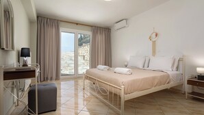 Une chambre à coucher avec un lit, un bureau, une chaise et une grande fenêtre.