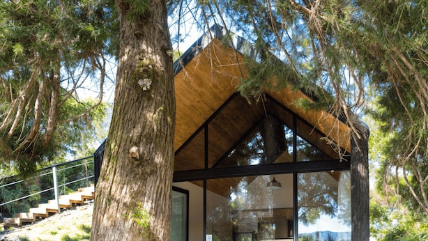 Un espace moderne aménagé à l’extérieur avec un jacuzzi, une terrasse en bois, une structure fermée par des parois de verre et un escalier menant à un niveau supérieur.