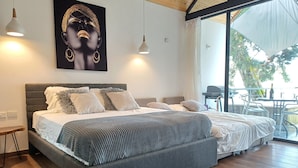 Une chambre moderne dotée d’un grand lit, offrant une vue sur l’extérieur et comprenant un balcon avec des sièges.