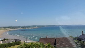 Uitzicht op de kust met een strand, zee en land in de verte.