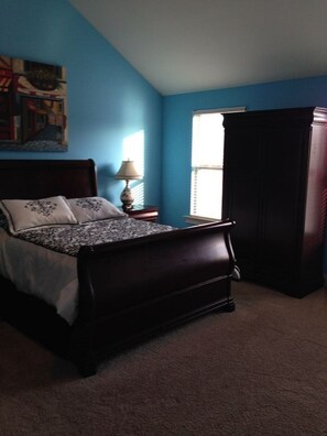 Cozy retreat with a dark wooden bed frame, bedside table, and large window.