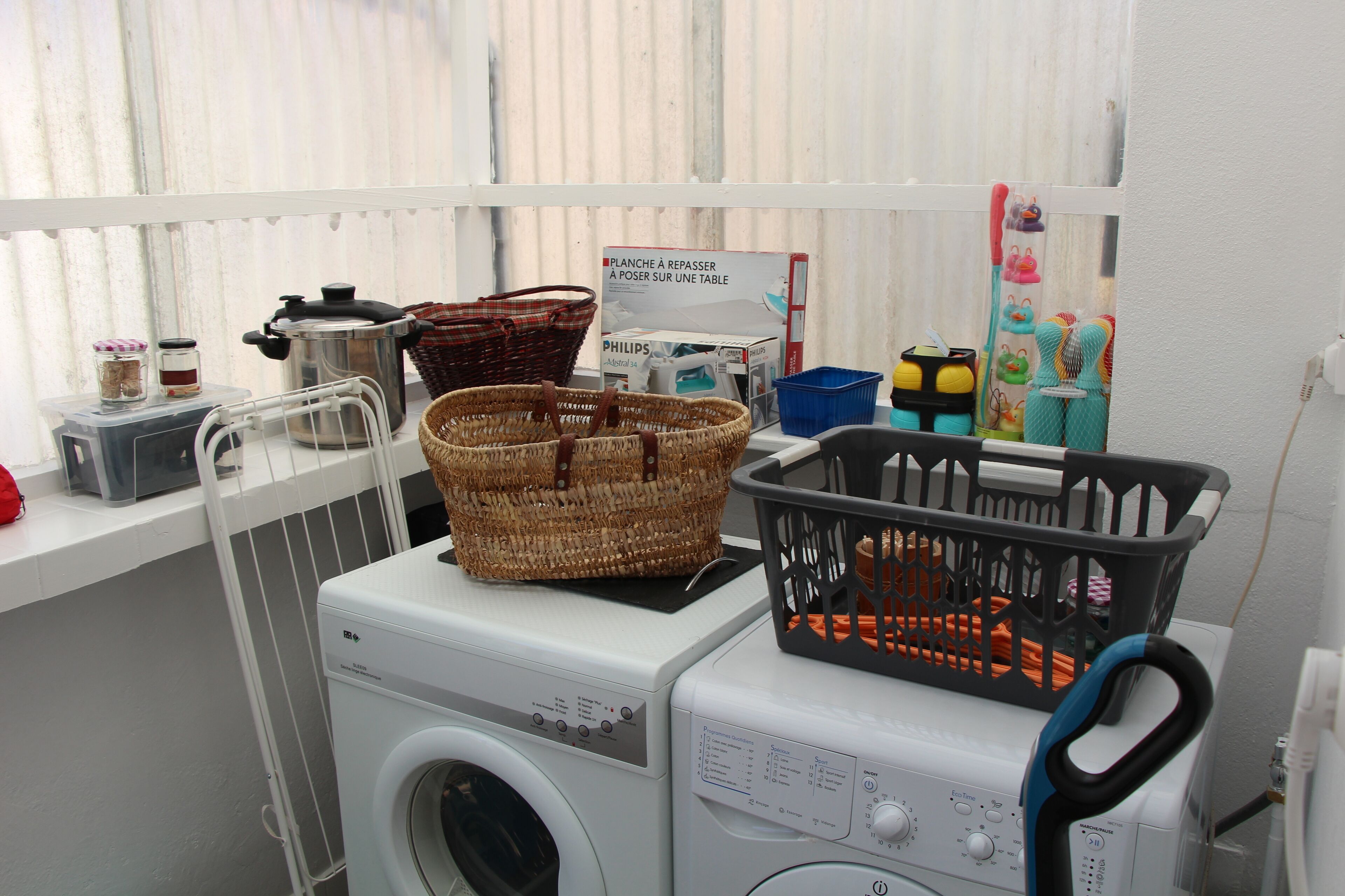 A laundry area with a washing machine, a dryer, and various baskets and containers.