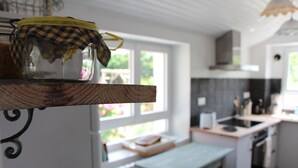 A kitchen with a window, a shelf with a jar, and a countertop.