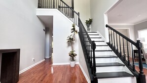 Una escalera con barandales negros y paredes blancas que conduce a un piso superior.