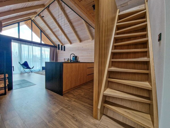 A modern kitchen with a wooden island, a built-in bench, and a staircase. - Luxury Chalet with Hot Tube & Sauna (Liptovský Mikuláš)