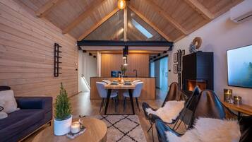 A modern interior with a dining area, leather chairs, a fireplace, and a wooden ceiling.