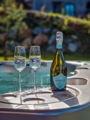 A bottle of Prosecco and two glasses on a table by a pool. - Luxury Chalet with Hot Tube & Sauna (Liptovský Mikuláš)