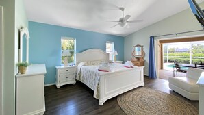 A bedroom with a bed, nightstands, a ceiling fan, a window, a mirror, and a view of the outdoors. - Turtle Bay, heated pool, 2 dogs ok, pool table (Rotonda West)