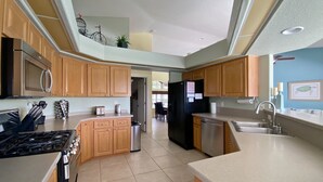 A modern kitchen with wooden cabinets, stainless steel appliances, and a visible island. - Turtle Bay, heated pool, 2 dogs ok, pool table (Rotonda West)